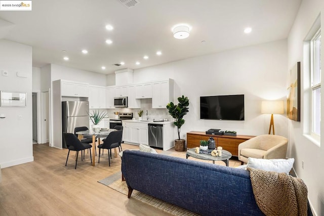 living room featuring sink and light hardwood / wood-style flooring