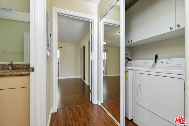 clothes washing area featuring dark wood-type flooring, cabinets, washing machine and clothes dryer, and sink