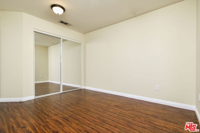 unfurnished bedroom featuring a closet and dark hardwood / wood-style flooring