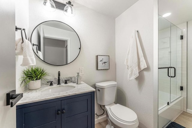 full bathroom featuring bath / shower combo with glass door, vanity, toilet, and hardwood / wood-style floors