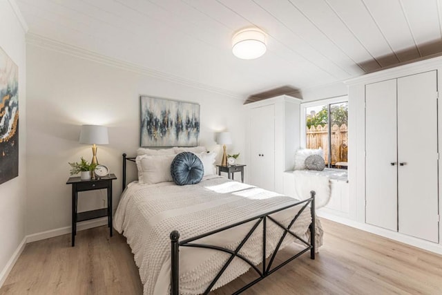 bedroom featuring crown molding, multiple closets, and light wood-type flooring