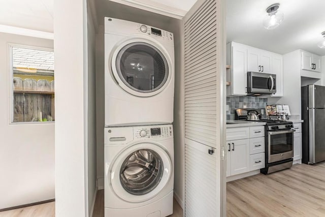 clothes washing area with stacked washer and dryer and light hardwood / wood-style floors