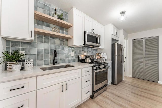 kitchen with white cabinetry, stainless steel appliances, sink, and backsplash