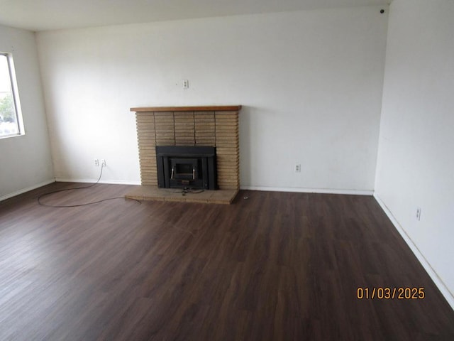 unfurnished living room with dark wood-type flooring and a fireplace