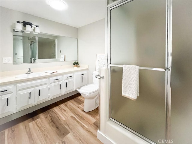 bathroom featuring an enclosed shower, vanity, toilet, and wood finished floors