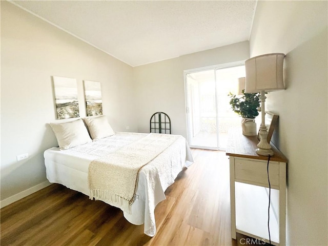 bedroom with baseboards, vaulted ceiling, and wood finished floors