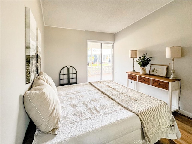 bedroom with access to outside and wood finished floors