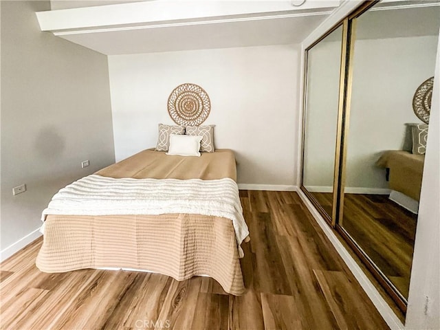 bedroom with a closet, baseboards, and wood finished floors