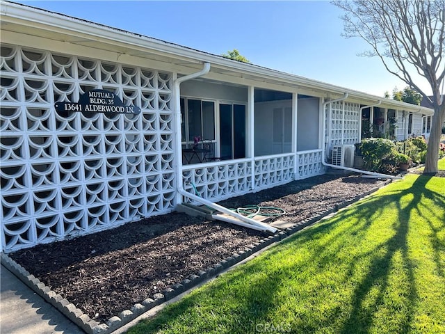 view of home's exterior featuring a sunroom and a lawn