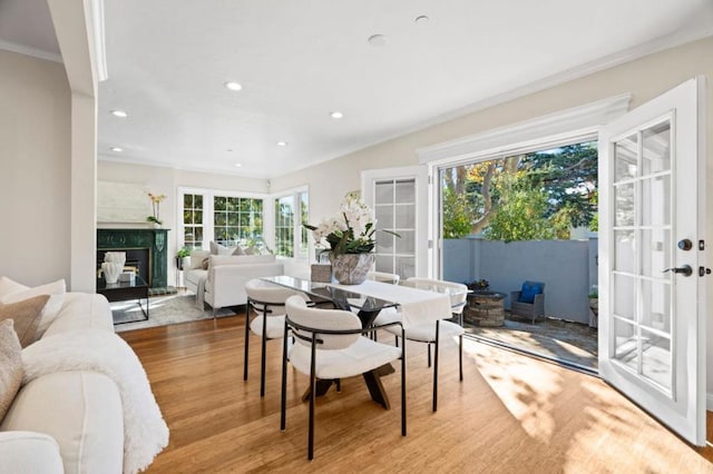 dining room featuring french doors, ornamental molding, a fireplace, and light hardwood / wood-style floors