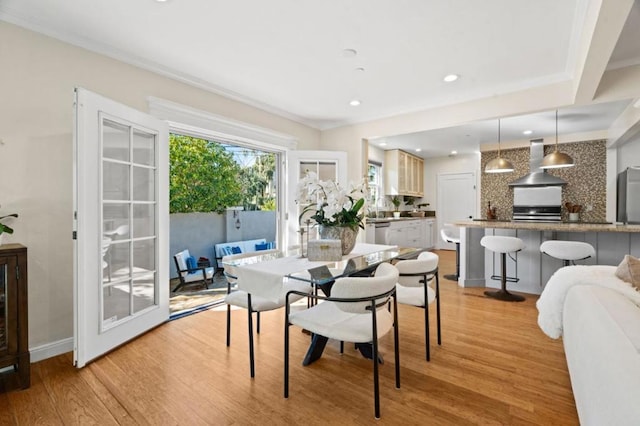 dining area with light hardwood / wood-style flooring and ornamental molding