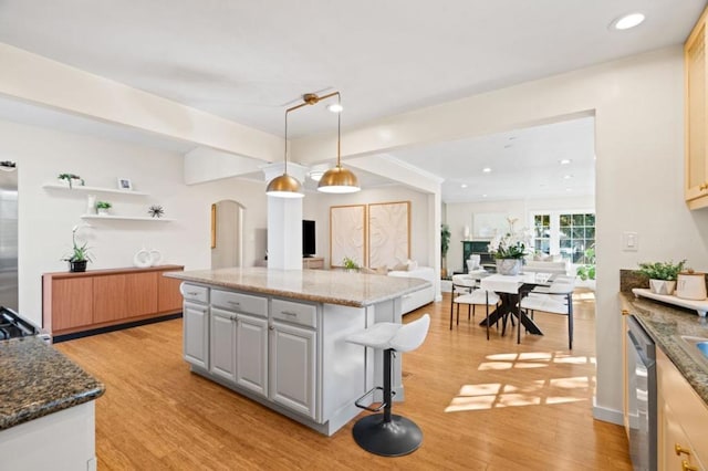 kitchen featuring decorative light fixtures, stainless steel dishwasher, gray cabinets, a kitchen island, and dark stone counters