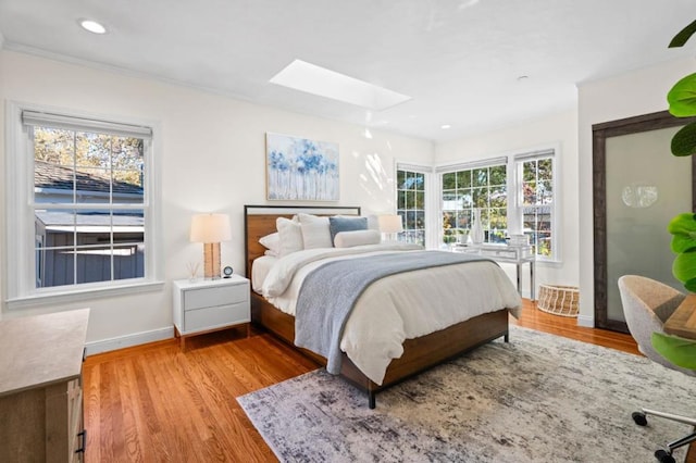 bedroom featuring a skylight and light hardwood / wood-style floors