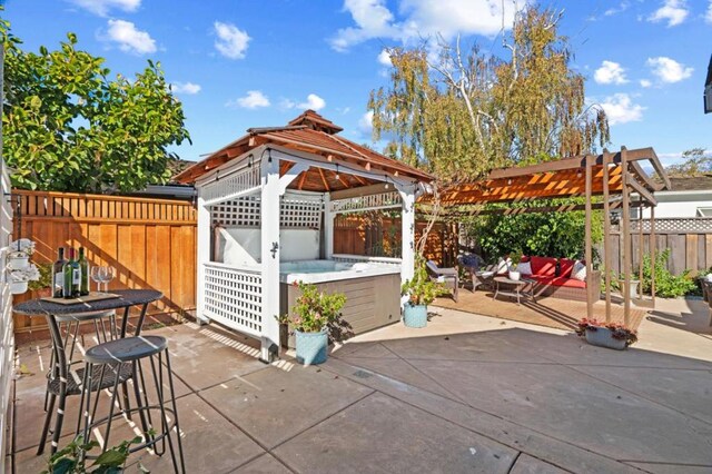 view of patio / terrace featuring a hot tub and a gazebo