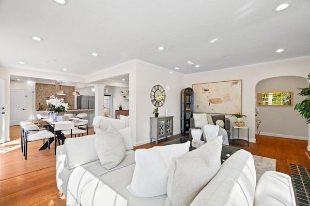 living room featuring ornate columns, wood-type flooring, and ornamental molding