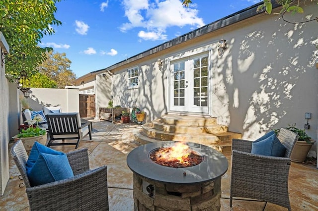 view of patio with an outdoor living space with a fire pit and french doors