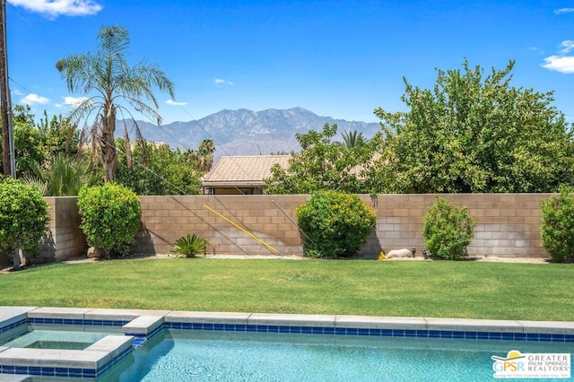 view of swimming pool with a mountain view, a yard, and an in ground hot tub