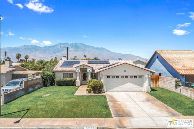 view of front of house featuring a mountain view, a front yard, a garage, and solar panels