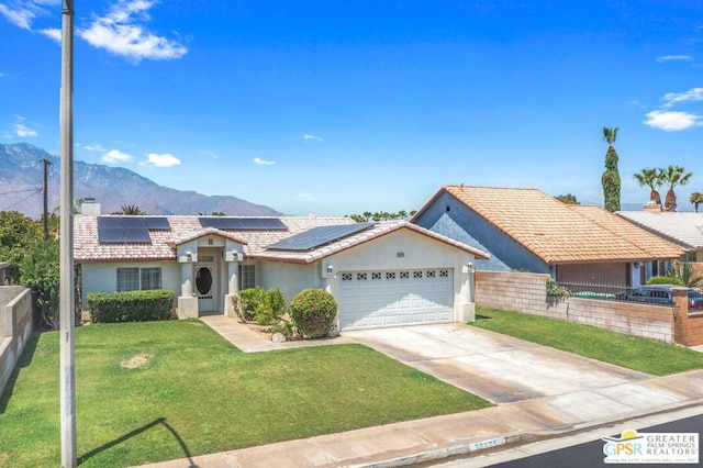 view of front of house featuring a mountain view, a front yard, a garage, and solar panels