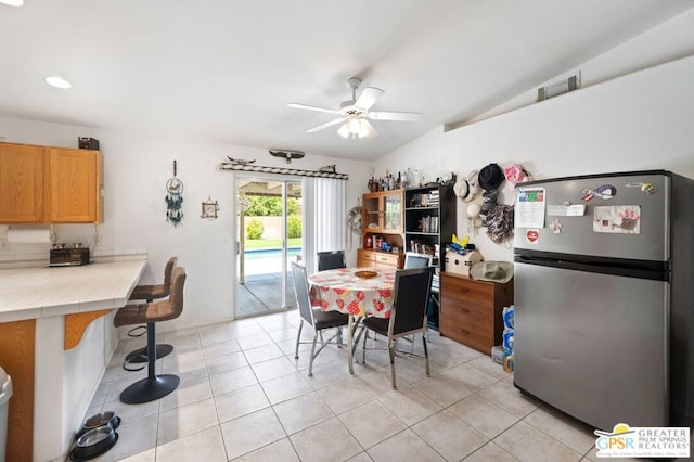 tiled dining area with ceiling fan and lofted ceiling