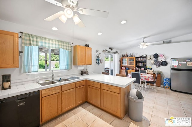 kitchen with kitchen peninsula, a wealth of natural light, sink, black dishwasher, and stainless steel fridge