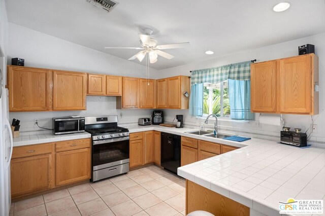 kitchen featuring light tile patterned floors, tile countertops, appliances with stainless steel finishes, lofted ceiling, and sink