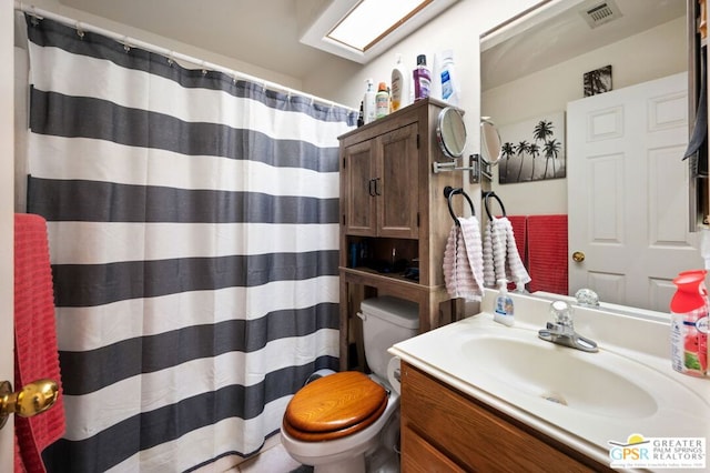 bathroom featuring toilet, vanity, and curtained shower