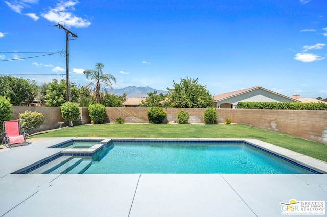 view of swimming pool with a lawn, a mountain view, and an in ground hot tub