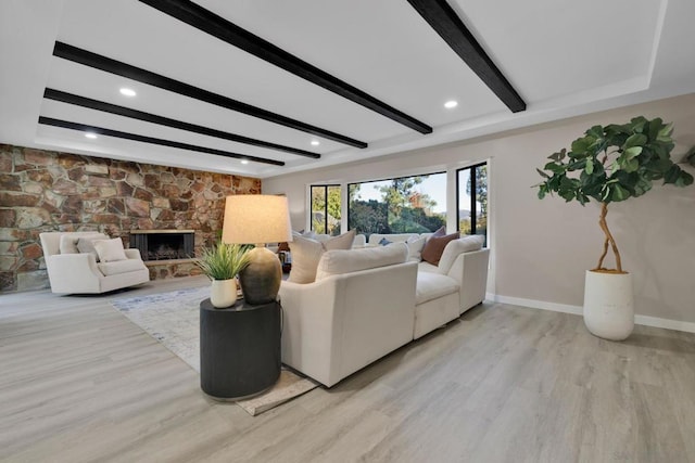 living room featuring a fireplace, light hardwood / wood-style flooring, and beamed ceiling