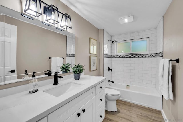 full bathroom with wood-type flooring, tiled shower / bath combo, vanity, and toilet