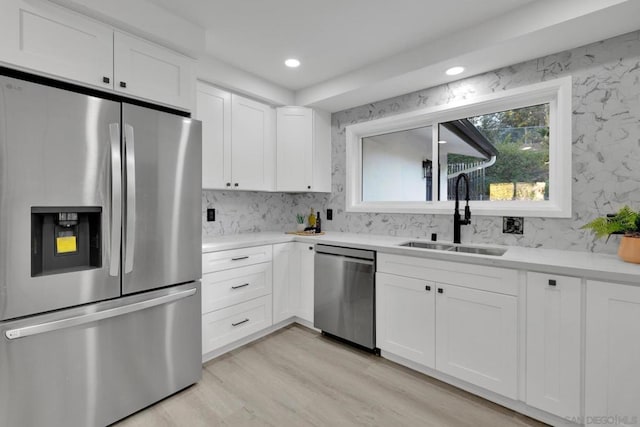 kitchen featuring white cabinets, appliances with stainless steel finishes, sink, and light hardwood / wood-style flooring