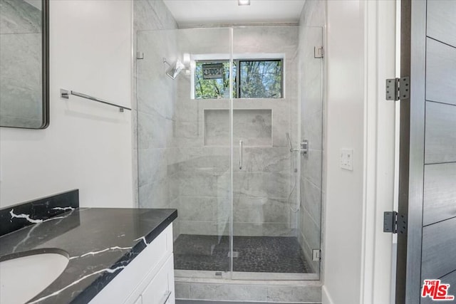 bathroom featuring a shower with shower door and vanity