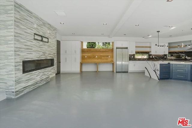 unfurnished living room featuring beam ceiling and a tiled fireplace