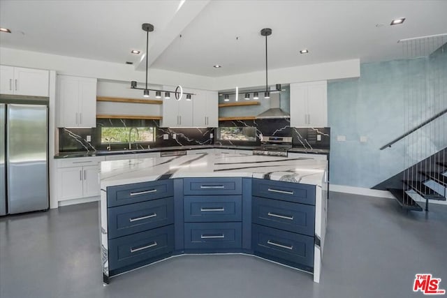 kitchen featuring dark stone counters, white cabinets, hanging light fixtures, and stainless steel refrigerator