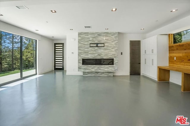 unfurnished living room featuring concrete floors and a tiled fireplace