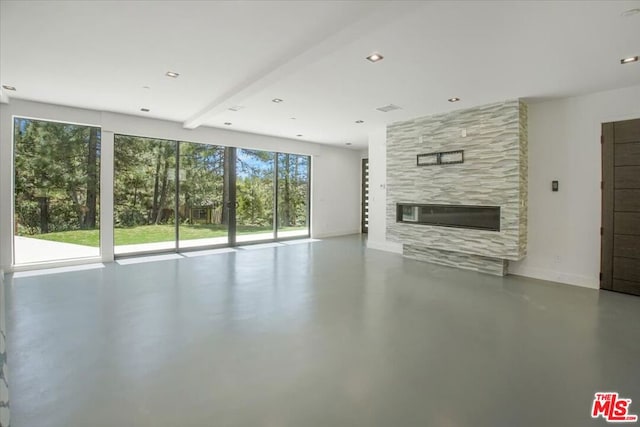 unfurnished living room with beam ceiling, a tiled fireplace, and concrete flooring