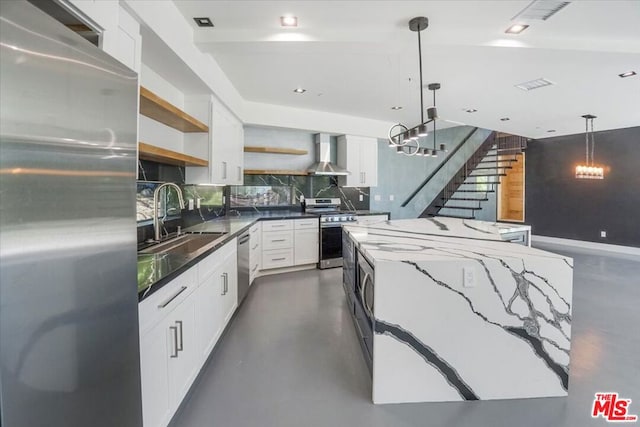 kitchen featuring stainless steel appliances, pendant lighting, white cabinets, and wall chimney range hood