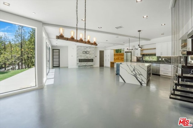 dining area featuring a healthy amount of sunlight, a stone fireplace, and a chandelier