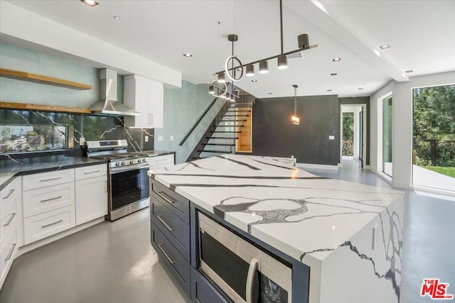 kitchen featuring backsplash, wall chimney exhaust hood, stainless steel appliances, and white cabinetry