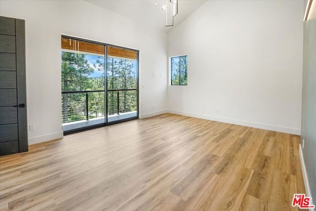 empty room featuring light wood-type flooring and high vaulted ceiling