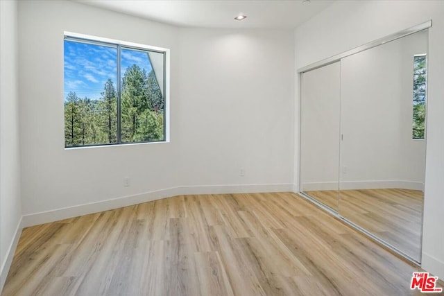 unfurnished bedroom featuring light wood-type flooring and a closet