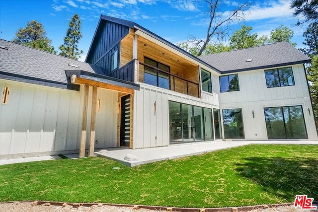 rear view of property with a lawn, a balcony, and a patio