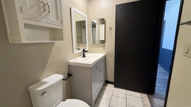 bathroom with toilet, tile patterned flooring, and vanity