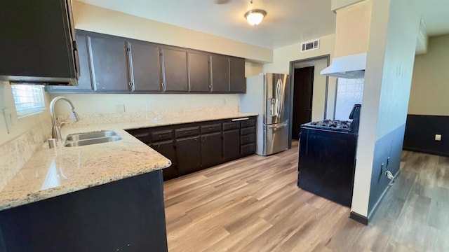 kitchen featuring stainless steel refrigerator with ice dispenser, sink, dark brown cabinetry, and light wood-type flooring