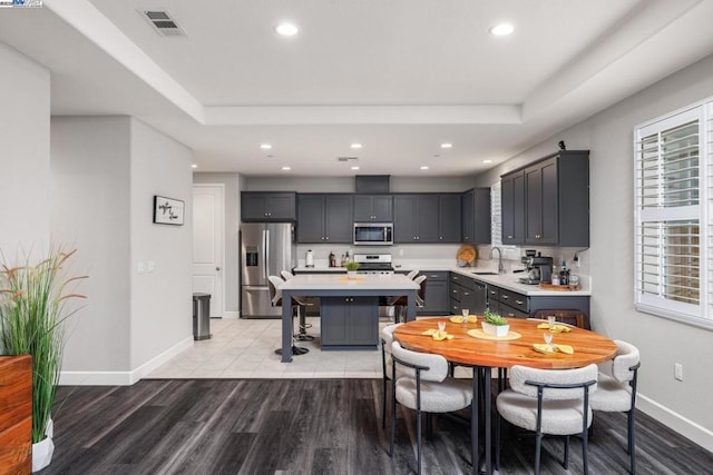 kitchen with a center island, stainless steel appliances, sink, gray cabinets, and light wood-type flooring