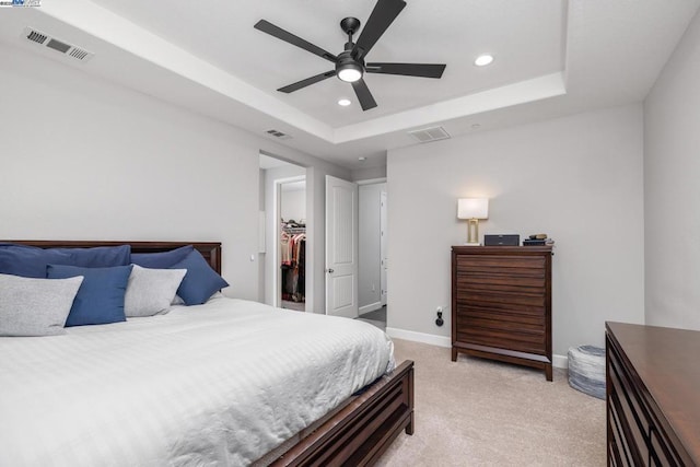 carpeted bedroom featuring a spacious closet, ceiling fan, a closet, and a raised ceiling