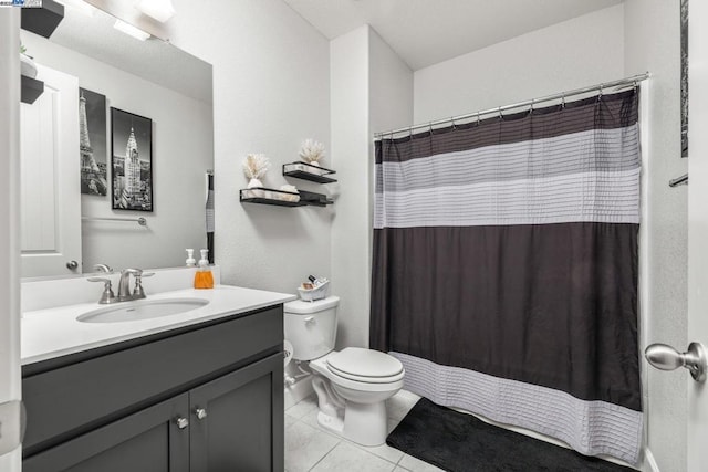 bathroom with toilet, vanity, and tile patterned flooring