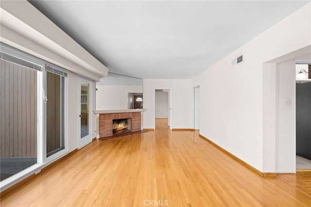 unfurnished living room with a brick fireplace and hardwood / wood-style floors