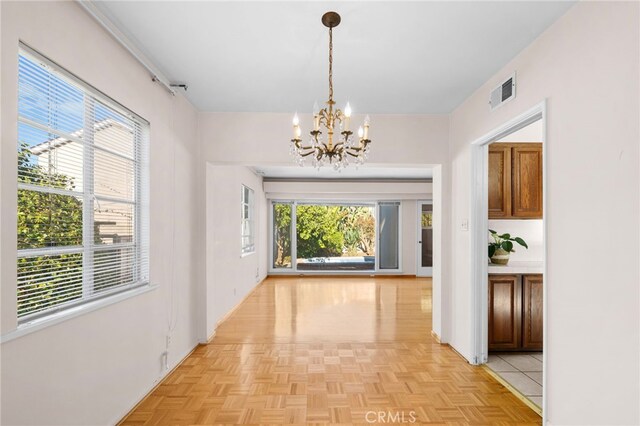 hall featuring light parquet floors and a chandelier