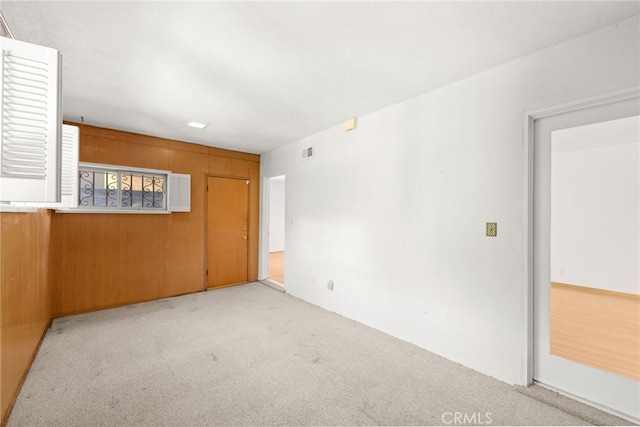 carpeted spare room with wooden walls